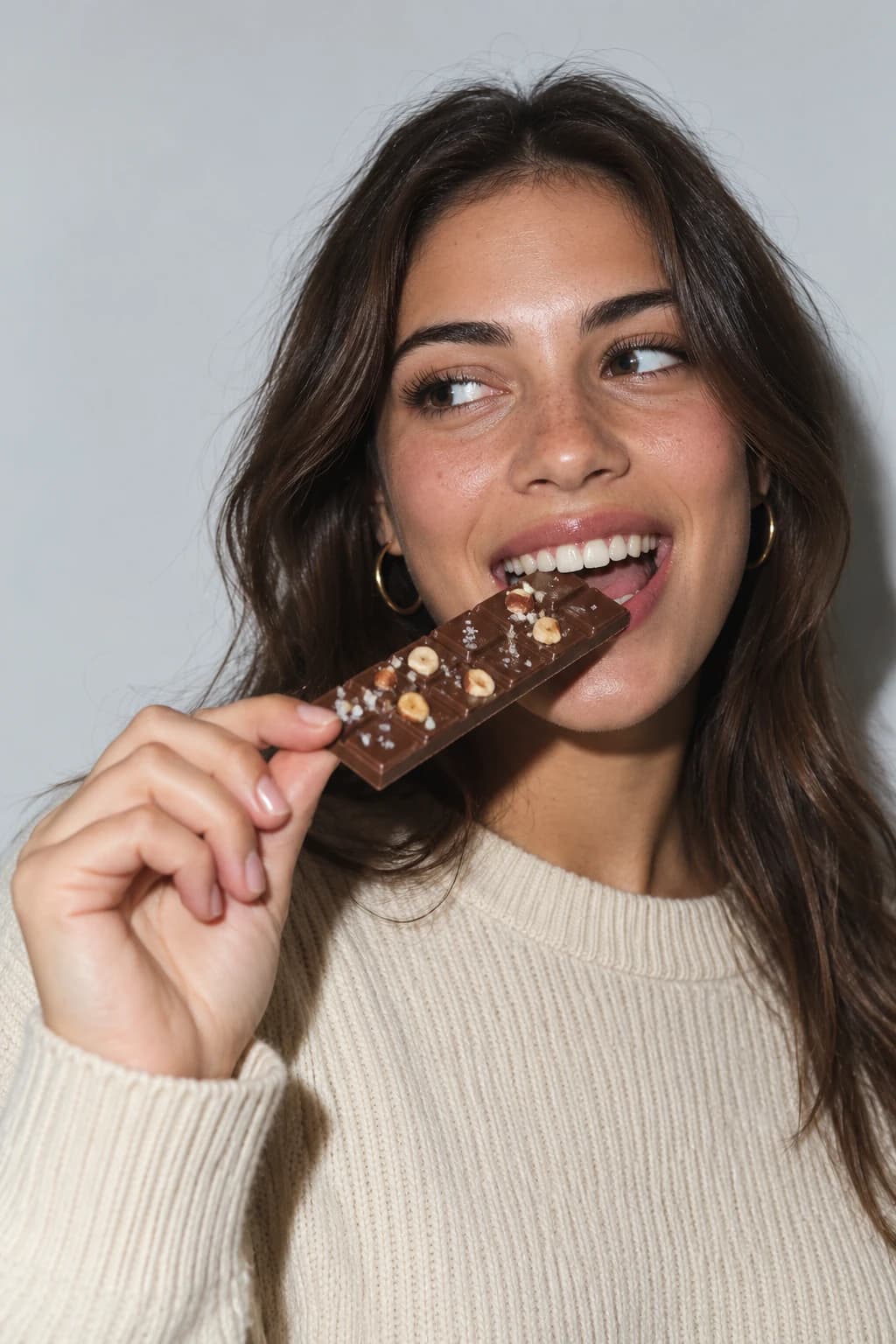 Chica sonriente mordiendo una tableta MELT de chocolate con leche y avellanas