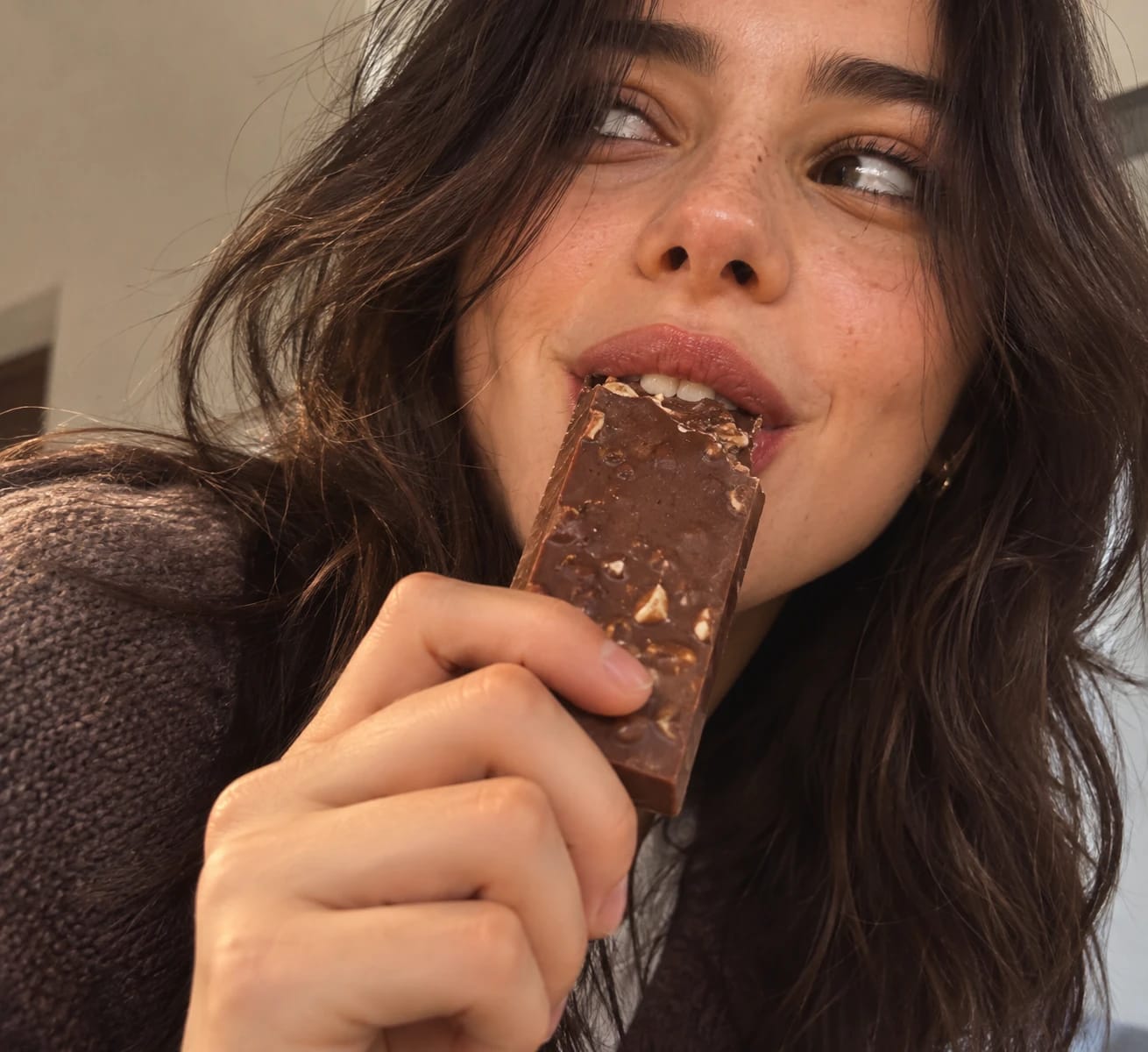 Primer plano de una chica mordiendo una tableta de chocolate MELT con frutos secos